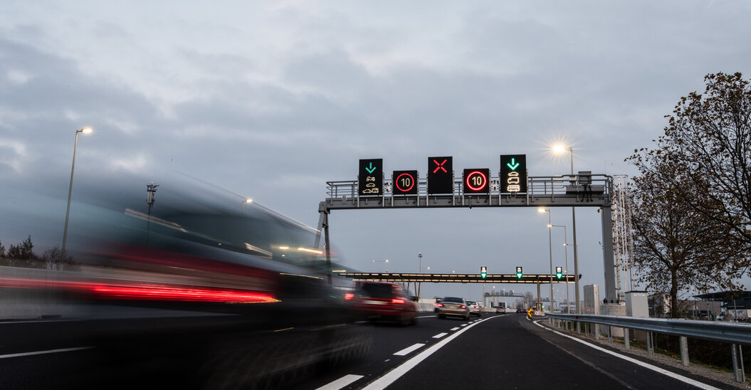 Elektronische Schilder auf einer Autobahn im Vordergrund vorbeifahrende Autos