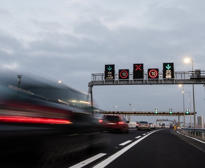 Elektronische Schilder auf einer Autobahn im Vordergrund vorbeifahrende Autos