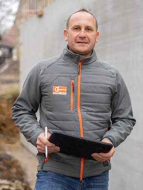 Leyrer + Graf Mitarbeiter steht mit Tablet auf einer Baustelle und blickt lächelnd in die Kamera