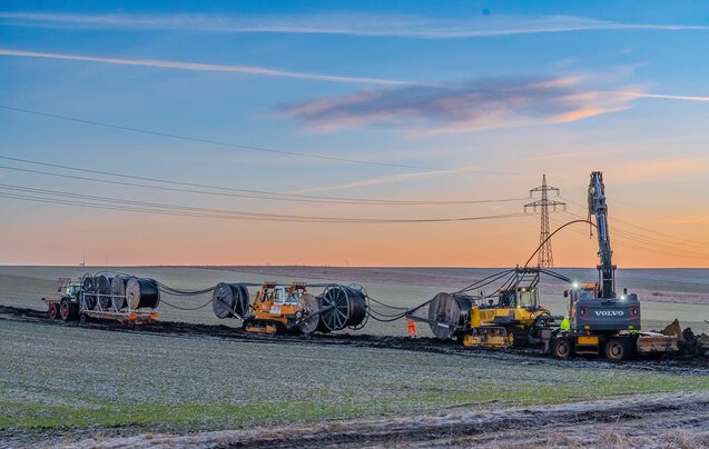 Zahlreiche Großgeräte, wie Kabelpflug beim verlegen einer Leitung im Sonnenaufgang