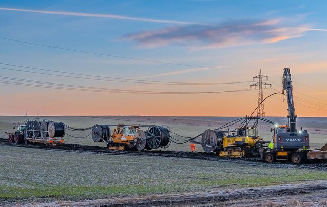 Zahlreiche Großgeräte, wie Kabelpflug beim verlegen einer Leitung im Sonnenaufgang