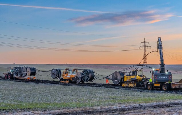 Zahlreiche Großgeräte, wie Kabelpflug beim verlegen einer Leitung im Sonnenaufgang