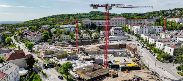 Leyrer + Graf Bauvorhaben Wohnhausanlage Grutschgasse, Mödling in der Bauphase mit rotem Kran und grüner und städtischer Umgebung Umgebung 