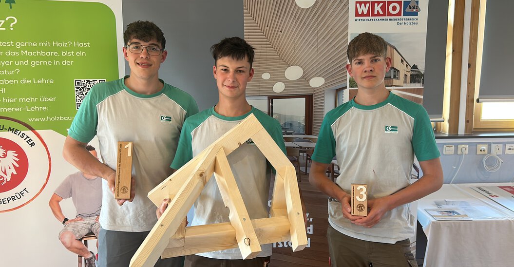 Drei Lehrlinge der Graf‑Holztechnik zeigen deren Pokale sowie das Bauwerks welches im Rahmen des Landeslehrlingswettbewerb der Zimmerer erarbeitet wurde