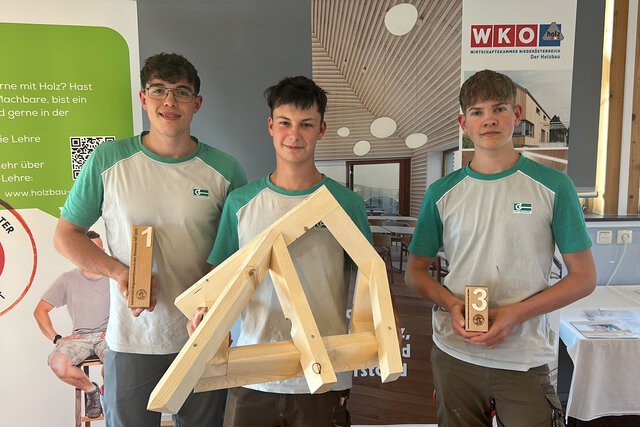 Drei Lehrlinge der Graf‑Holztechnik zeigen deren Pokale sowie das Bauwerks welches im Rahmen des Landeslehrlingswettbewerb der Zimmerer erarbeitet wurde