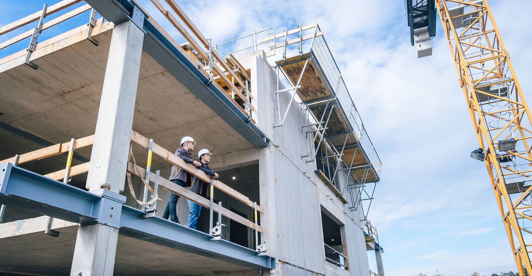 Zwei Leyrer + Graf Mitarbeiter stehen erhöht auf einer Baustelle und besprechen das weiter Vorgehen auf der Baustelle