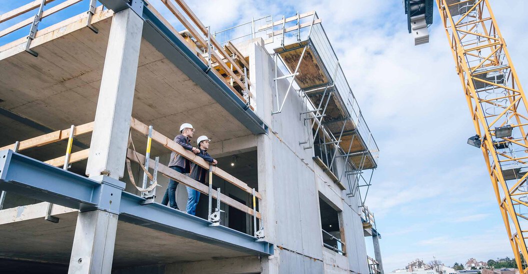 Zwei Leyrer + Graf Mitarbeiter stehen erhöht auf einer Baustelle und besprechen das weiter Vorgehen auf der Baustelle