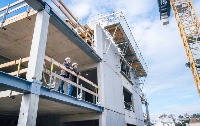 Zwei Leyrer + Graf Mitarbeiter stehen erhöht auf einer Baustelle und besprechen das weiter Vorgehen auf der Baustelle
