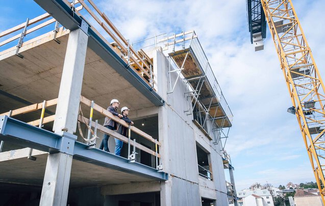 Zwei Leyrer + Graf Mitarbeiter stehen erhöht auf einer Baustelle und besprechen das weiter Vorgehen auf der Baustelle