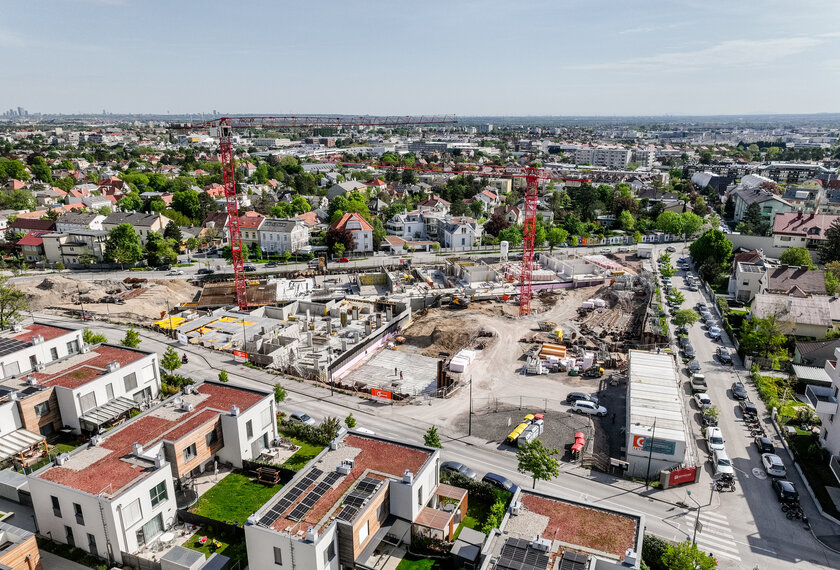 Leyrer + Graf Bauvorhaben Wohnhausanlage Grutschgasse, Mödling in der Bauphase mit rotem Kran und grüner und städtischer Umgebung 
