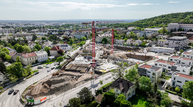 Leyrer + Graf Bauvorhaben Wohnhausanlage Grutschgasse, Mödling in der Bauphase mit rotem Kran und grüner und städtischer Umgebung 