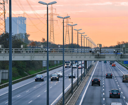 Stadteinfahrt im Sonnenuntergang im Fokus steht die Straßenbeleuchtung