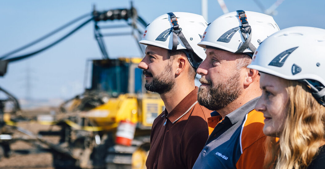 Drei Leyrer + Graf Mitarbeiter stehen hintereinander auf einer Baustelle und Blicken in die Ferne
