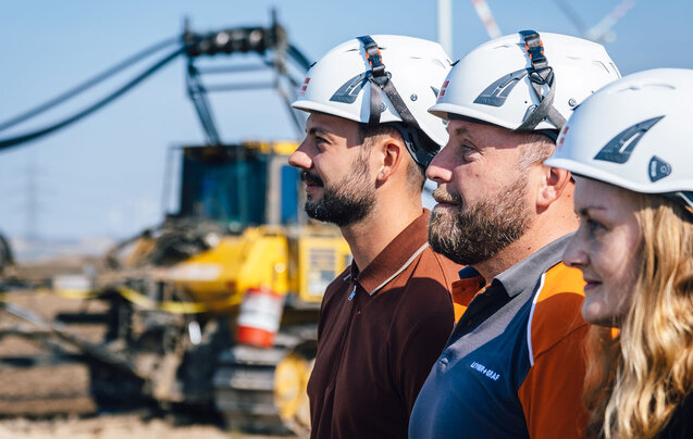 Drei Leyrer + Graf Mitarbeiter stehen hintereinander auf einer Baustelle und Blicken in die Ferne