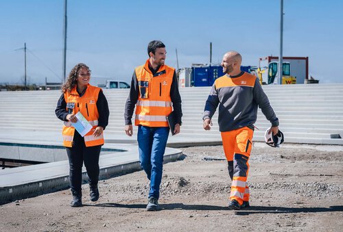 Drei Leyrer + Graf Mitarbeiter gehen auf einer Baustelle nebeneinander und unterhalten sich dabei