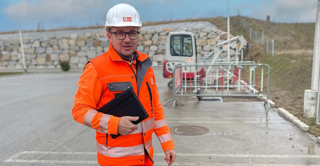 Leyrer + Graf Mitarbeiter steht vor einer Baustelle und lächelt in die Kamera