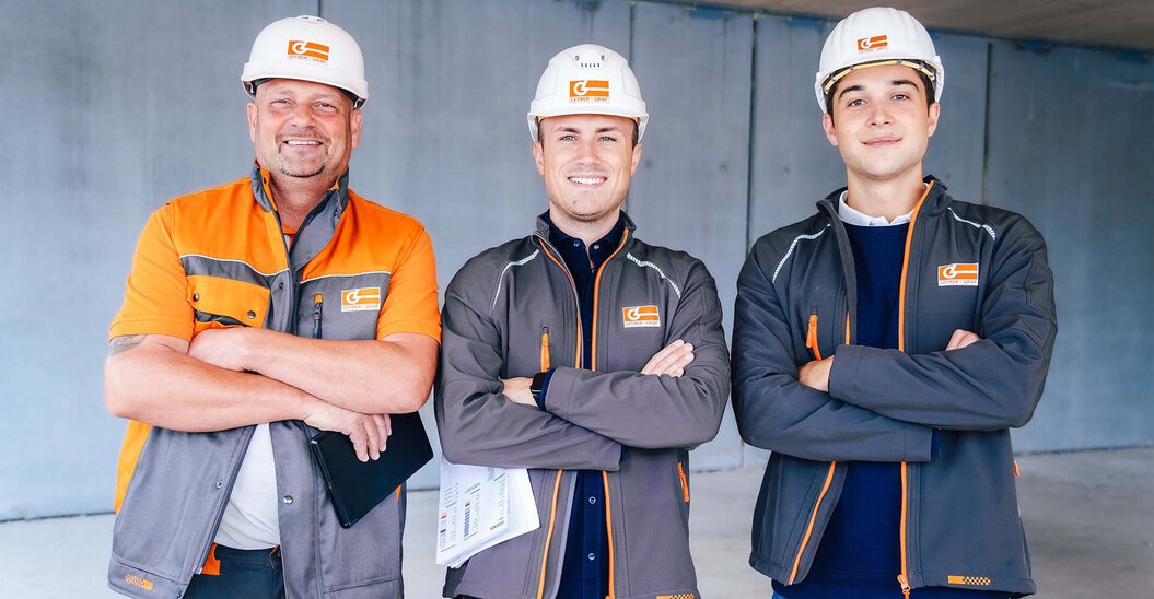Drei Leyrer + Graf Mitarbeiter stehen auf einer Baustelle haben verschränkte Arme und blicken direkt in die Kamera mit einem lächeln
