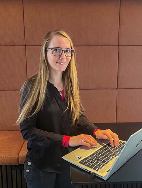 Leyrer + Graf Mitarbeiterin arbeitet am Laptop und lächelt in die Kamera