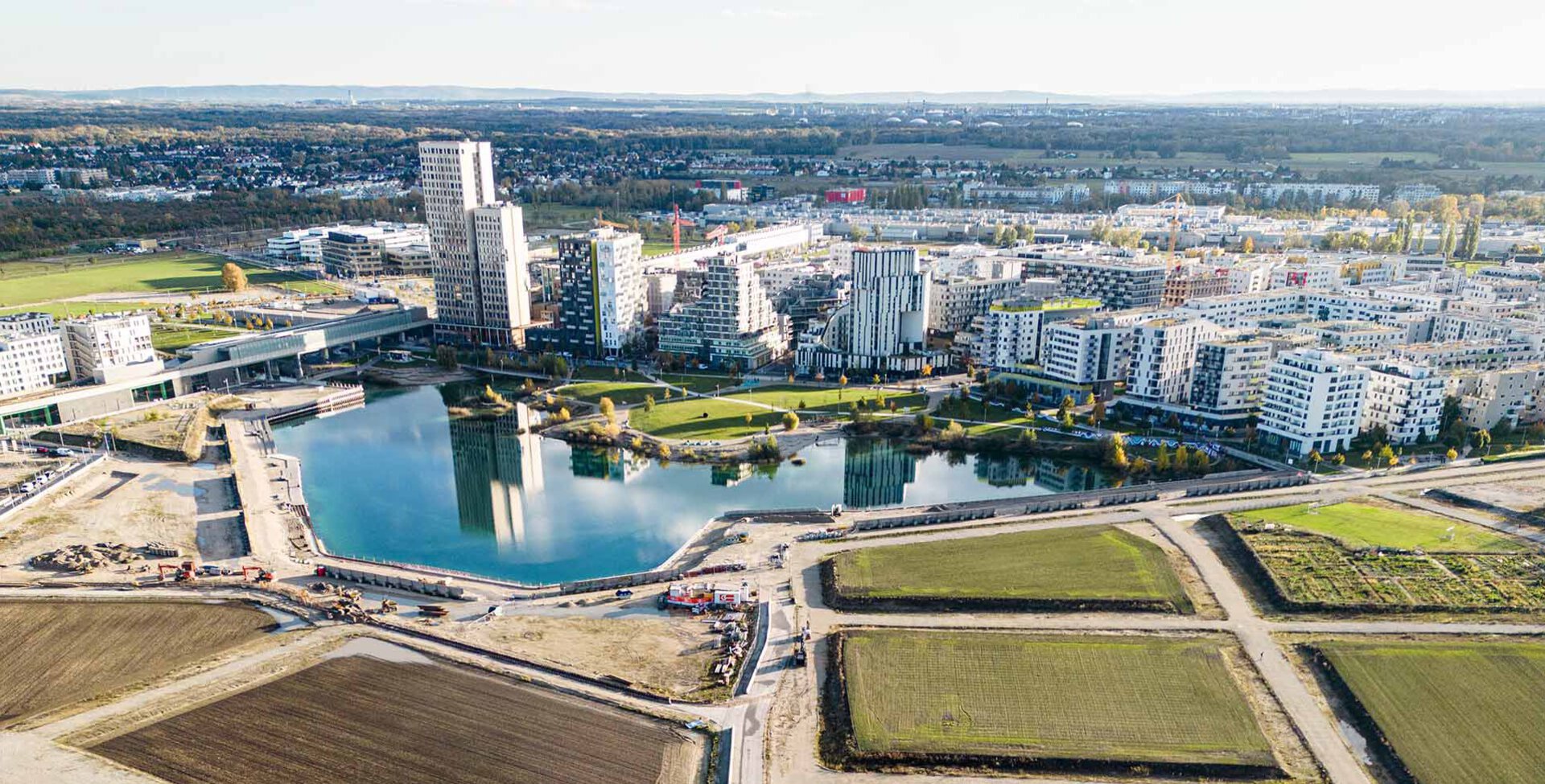 Tiefbau Bauvorhaben Leyrer + Graf - See wird auf einer Seite von Gebäuden umkreist und von der anderen Seite führen noch nicht fertiggestellt Straßen und Wege zum See und zur Stadt