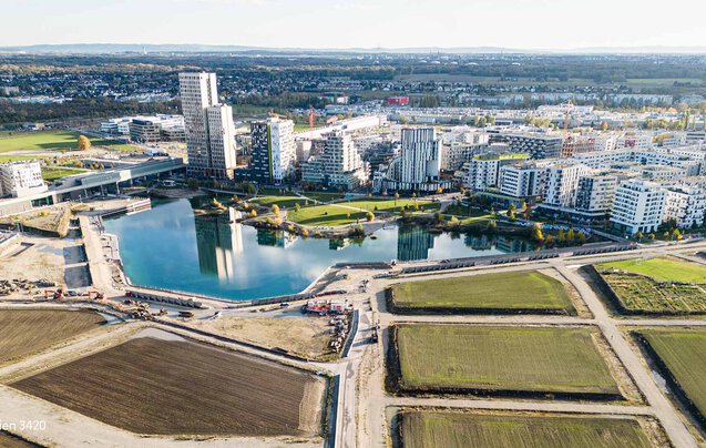 Tiefbau Bauvorhaben Leyrer + Graf - See wird auf einer Seite von Gebäuden umkreist und von der anderen Seite führen noch nicht fertiggestellt Straßen und Wege zum See und zur Stadt