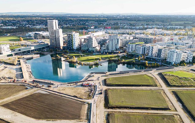 Tiefbau Bauvorhaben Leyrer + Graf - See wird auf einer Seite von Gebäuden umkreist und von der anderen Seite führen noch nicht fertiggestellt Straßen und Wege zum See und zur Stadt